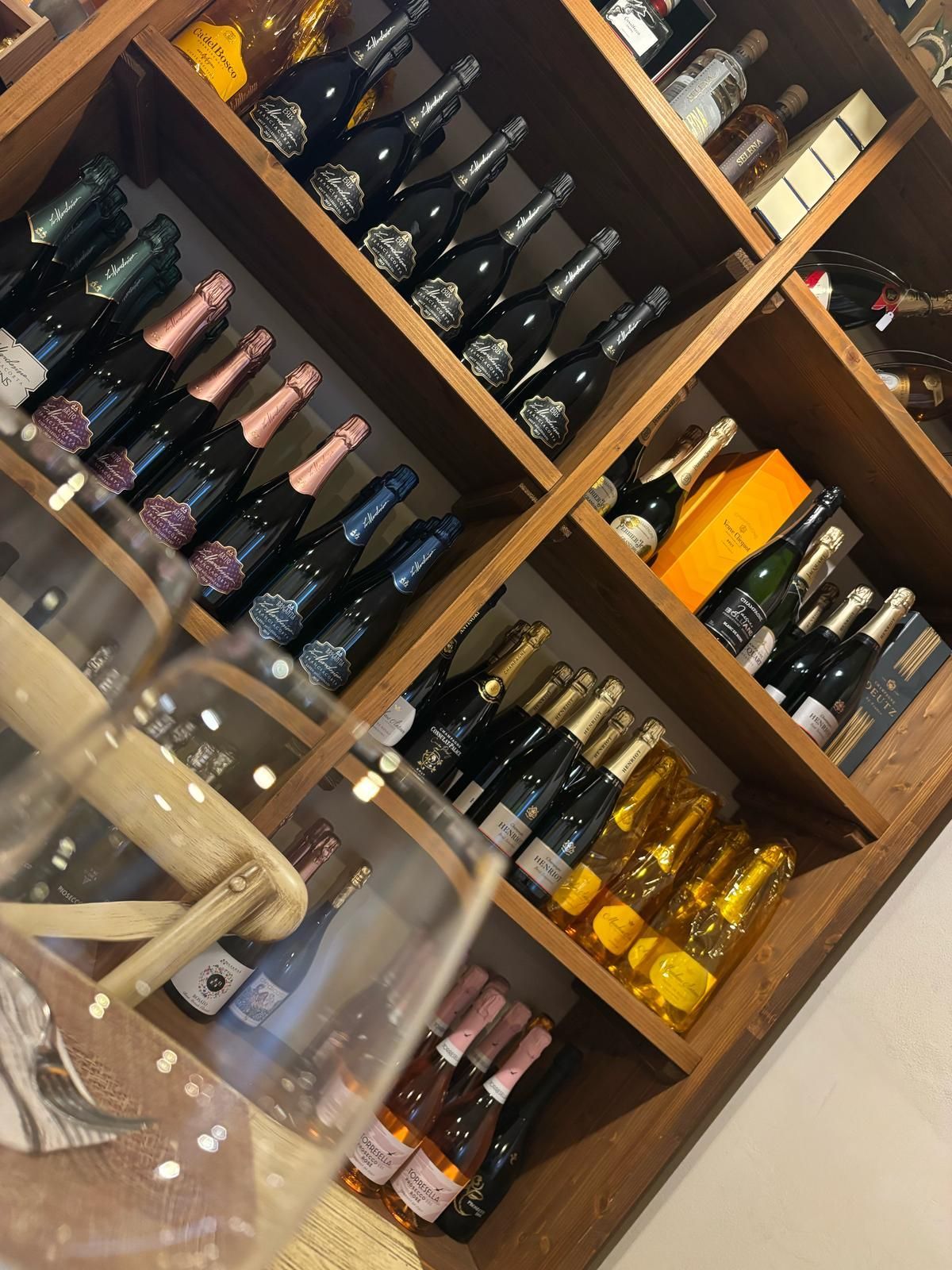 Uno scaffale pieno di bottiglie di vino tra cui una bottiglia di veuve clicquot