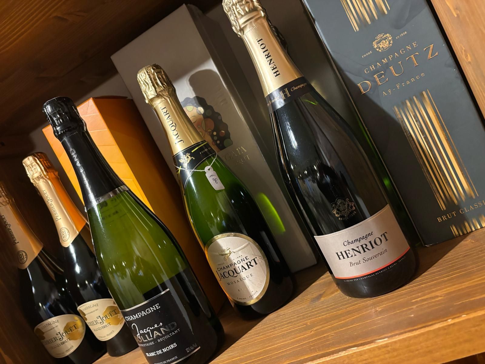 Diverse bottiglie di champagne sono allineate su uno scaffale di legno