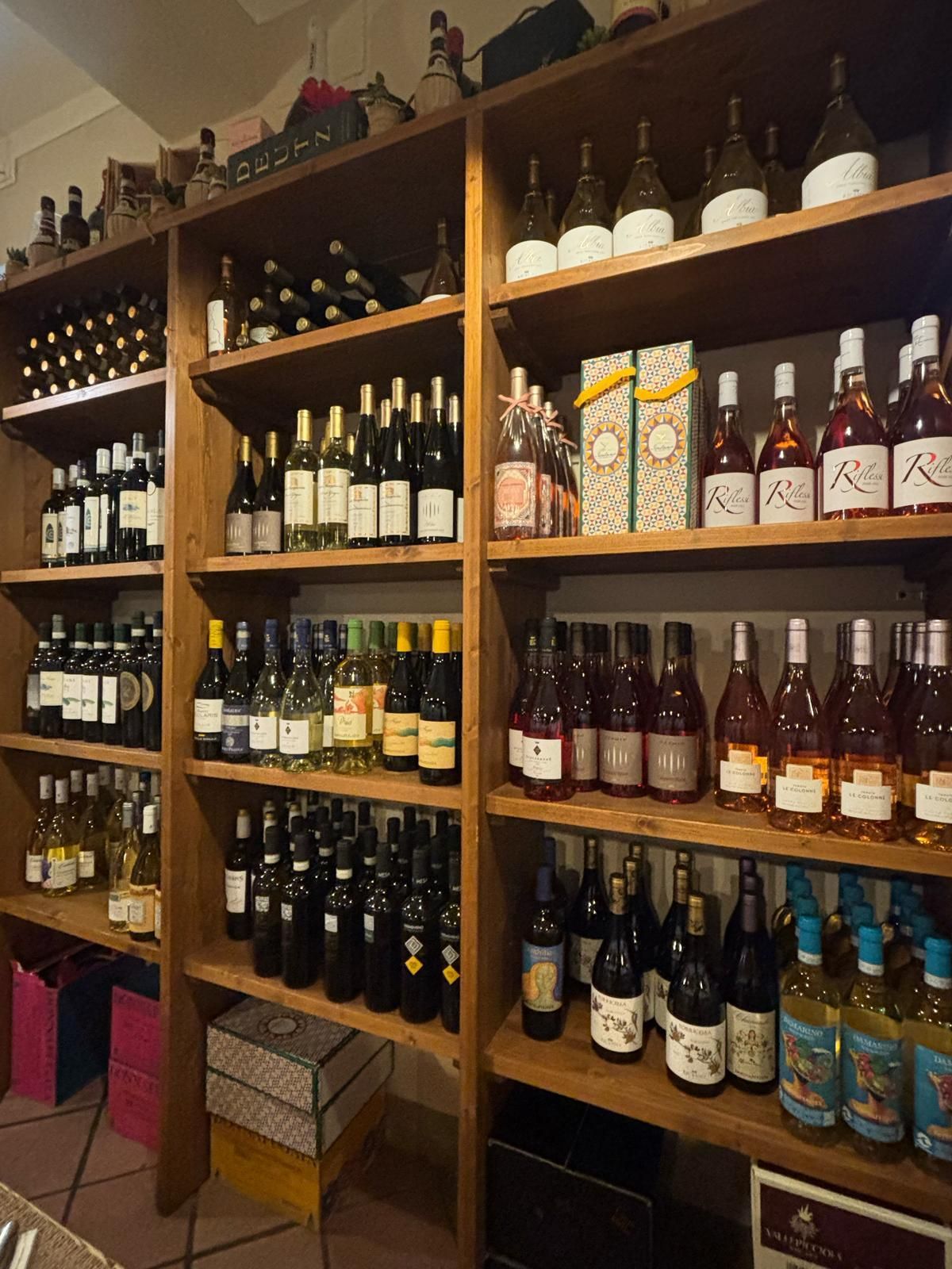 Scaffali pieni di bottiglie di vino, tra cui una con la scritta 