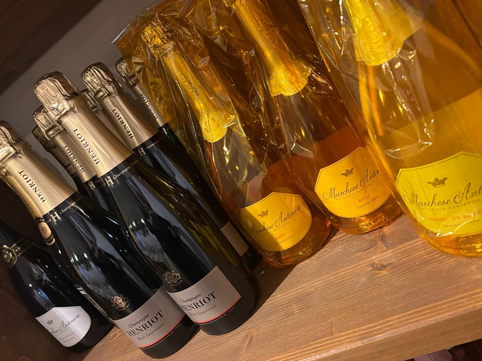 Diverse bottiglie di champagne sono allineate su uno scaffale di legno