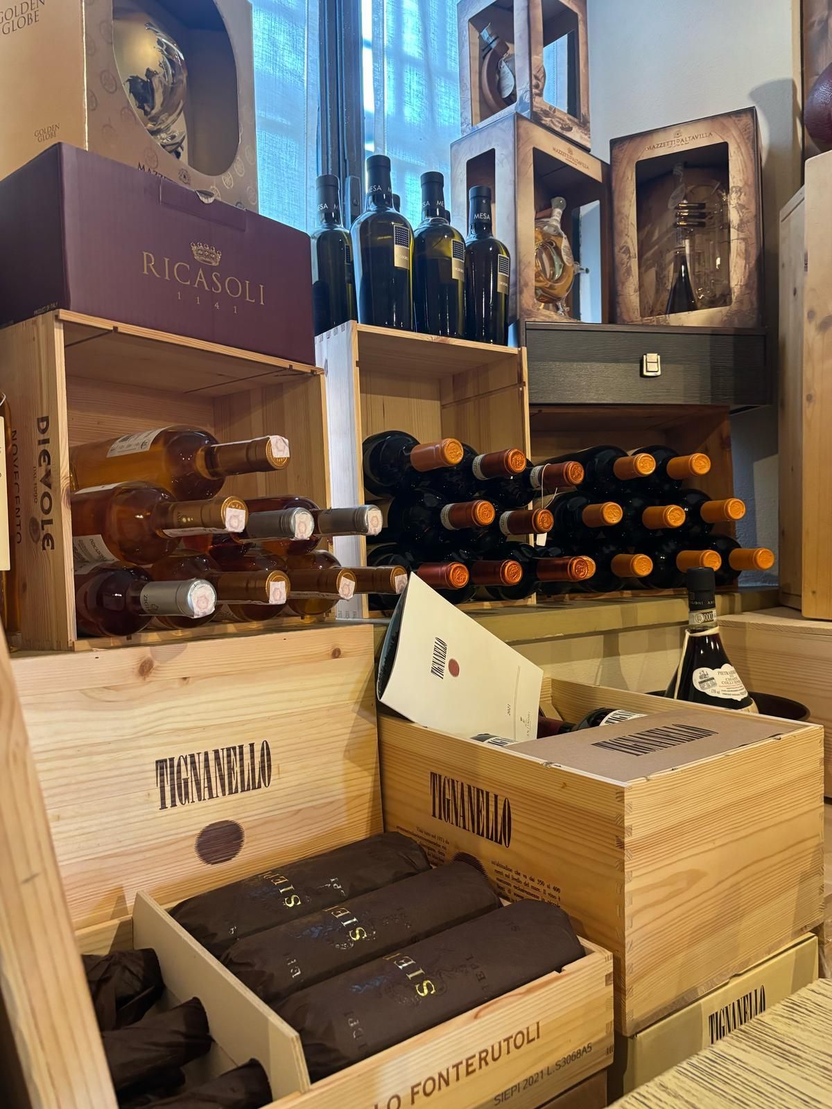 Un mucchio di bottiglie di vino sono accatastate l'una sull'altra in casse di legno.