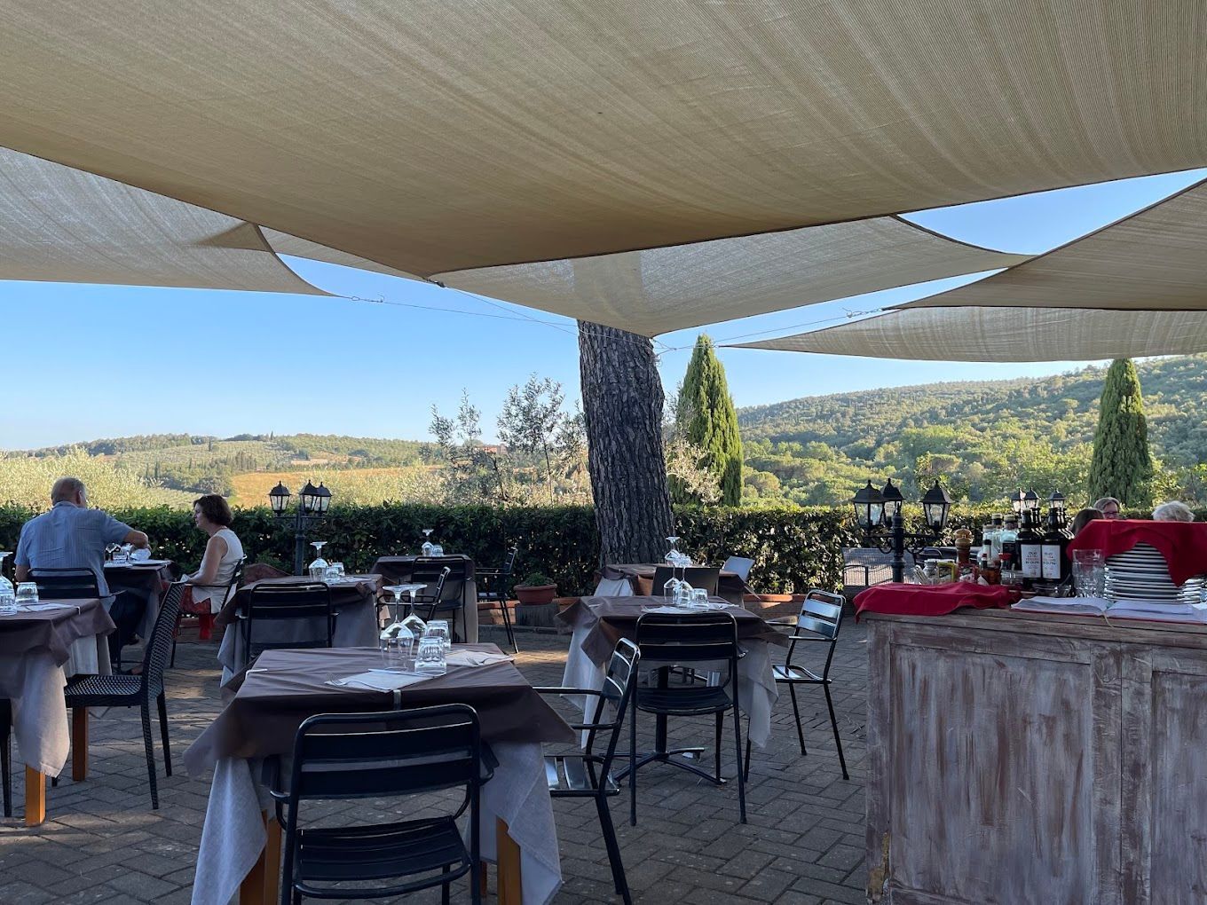 Un gruppo di persone è seduto ai tavoli sotto gli ombrelloni di un ristorante.