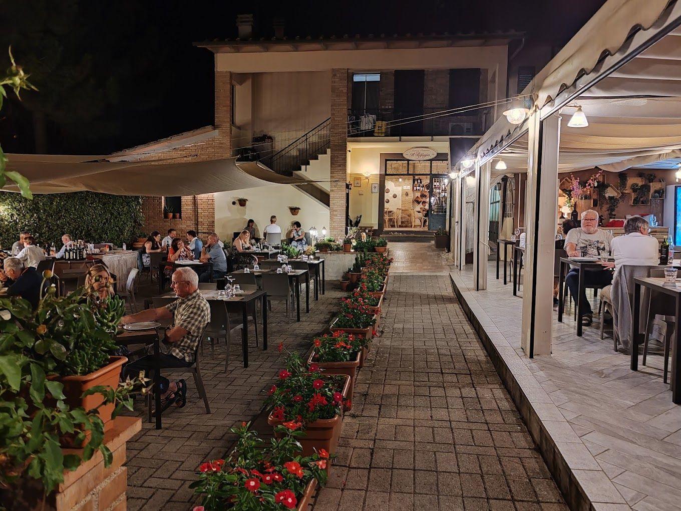 Un gruppo di persone è seduto ai tavoli di un ristorante di notte.