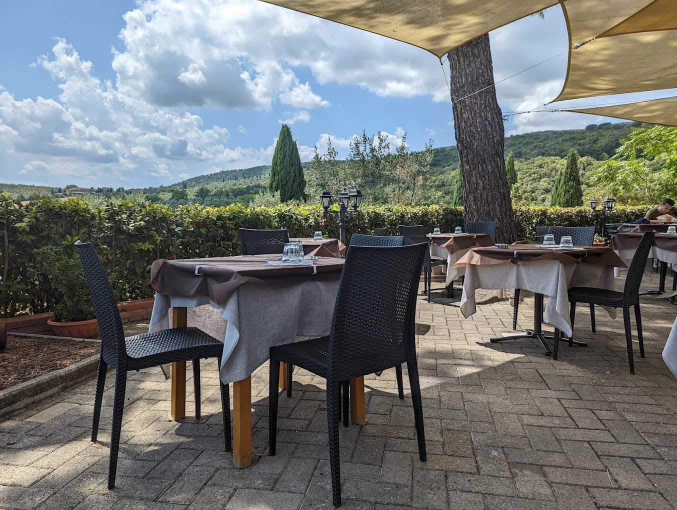 Un patio del ristorante con tavoli e sedie sotto una tettoia.