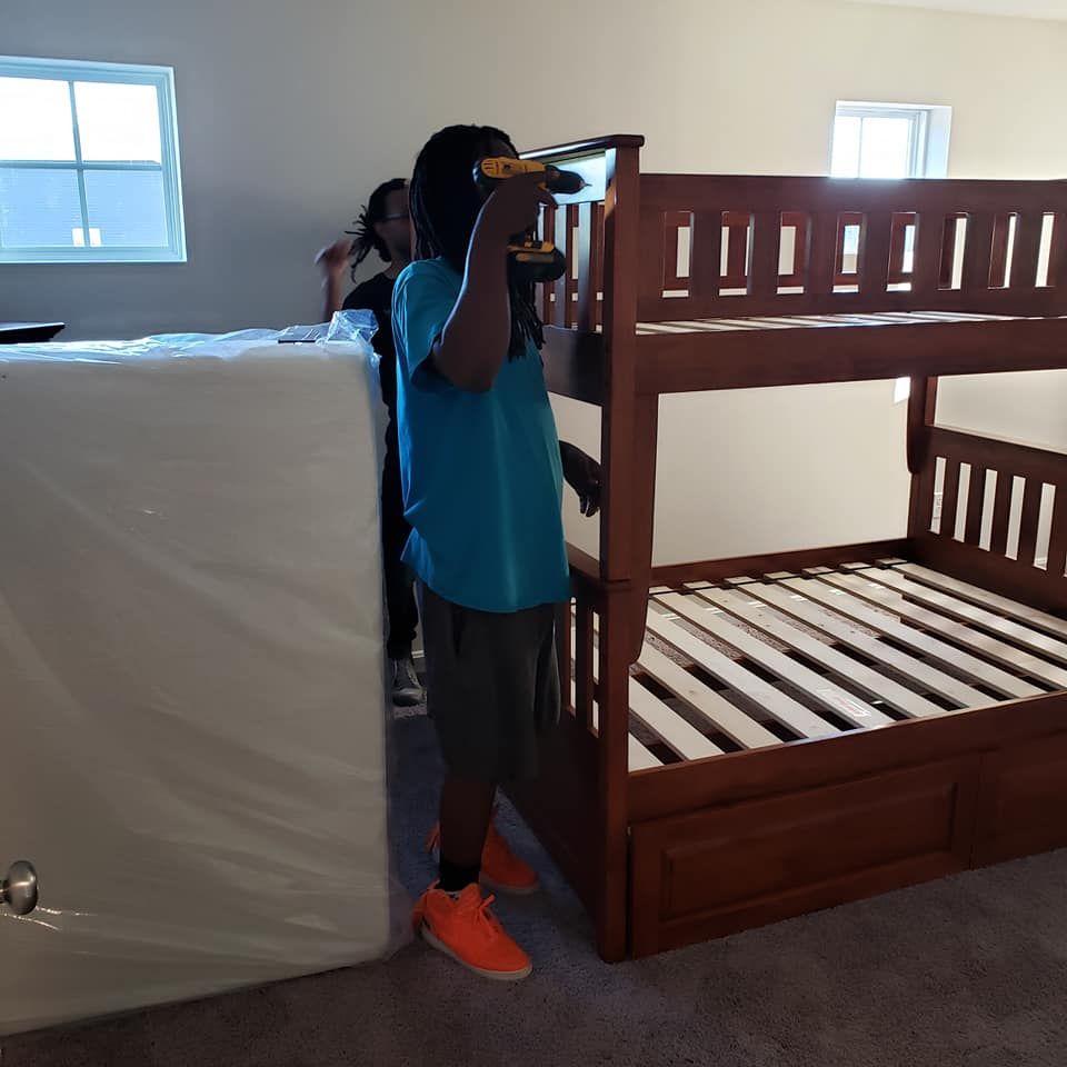 A man in a blue shirt is working on a bunk bed