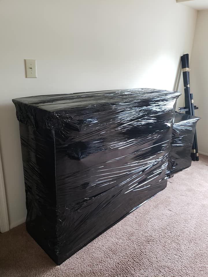 A dresser is wrapped in plastic wrap in a room.