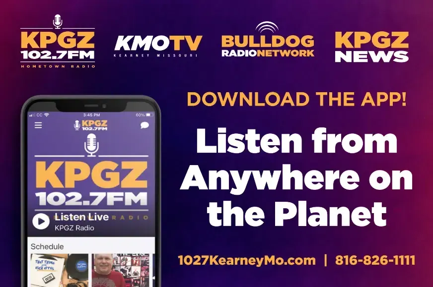 Advertisement for KPGZ 102.7FM radio app. Dark purple background with the app on a phone showing the station's logo. The text says 