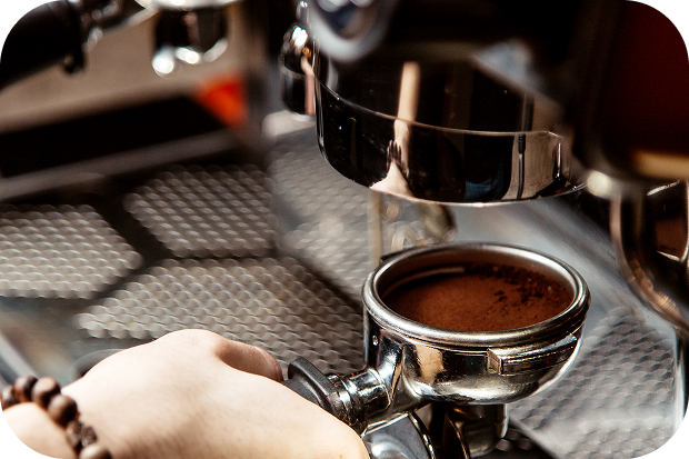Espresso machine dispensing coffee into a portafilter held by a person.