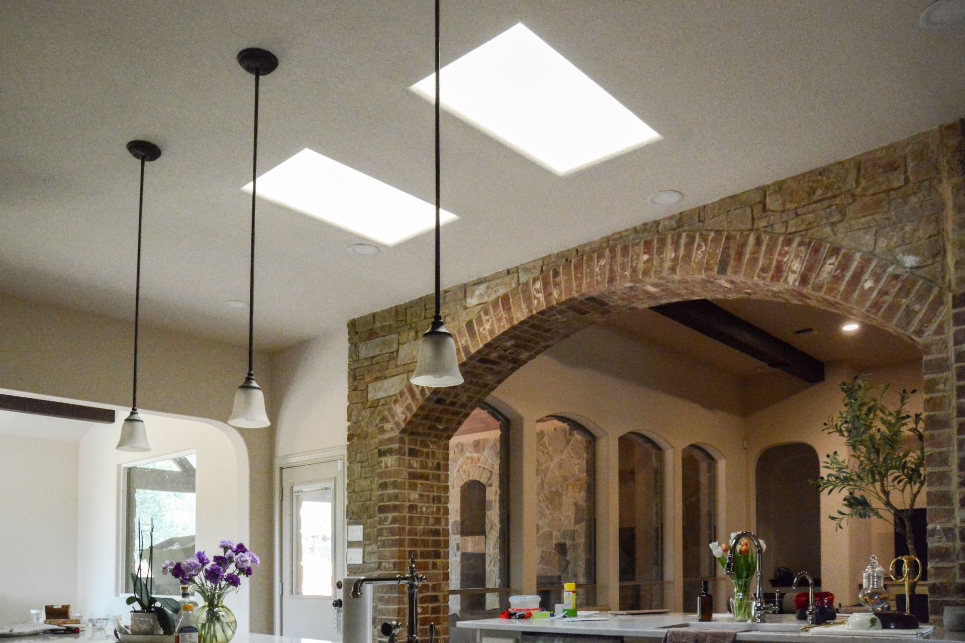 Kitchen with hanging lights, skylights, brick archway, and countertops.