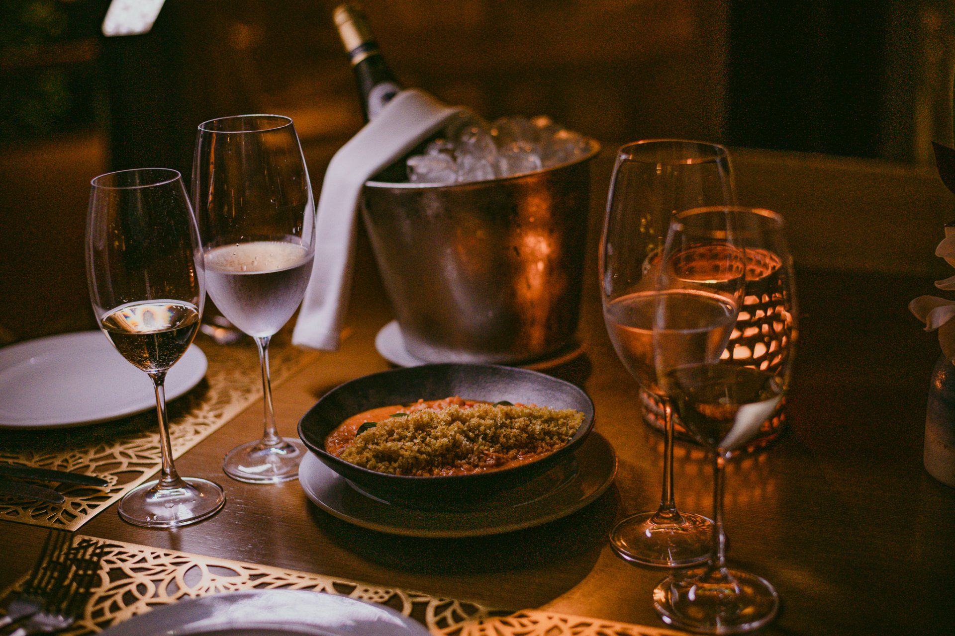 Uma mesa posta à luz de velas para um jantar com champanhe, um prato e taças.