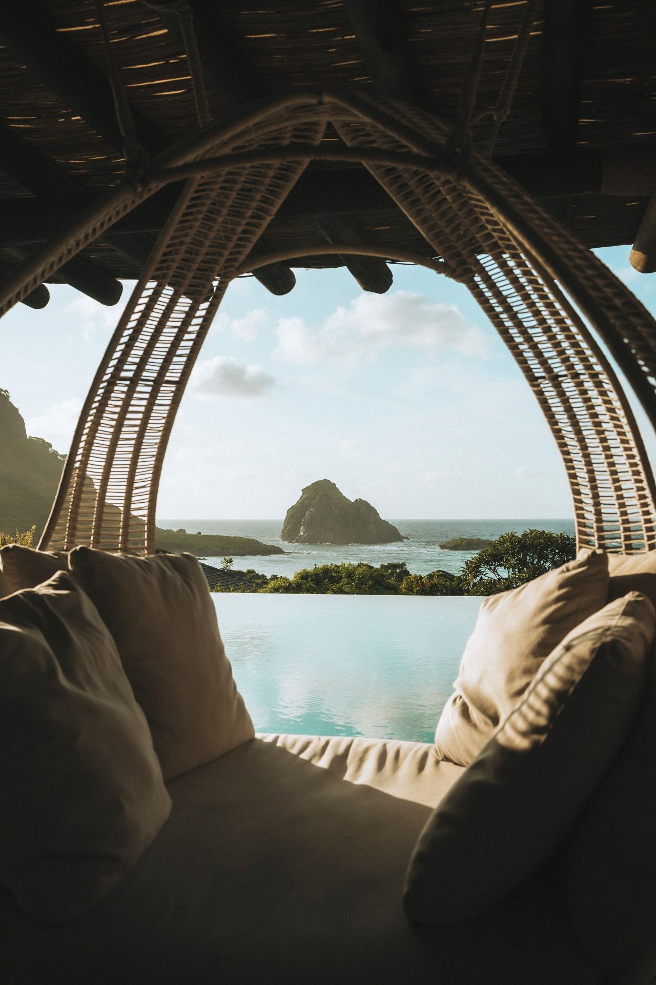 Piscina de borda infinita com deck de madeira, cabana e vista para o mar com vista para o pico da ilha.