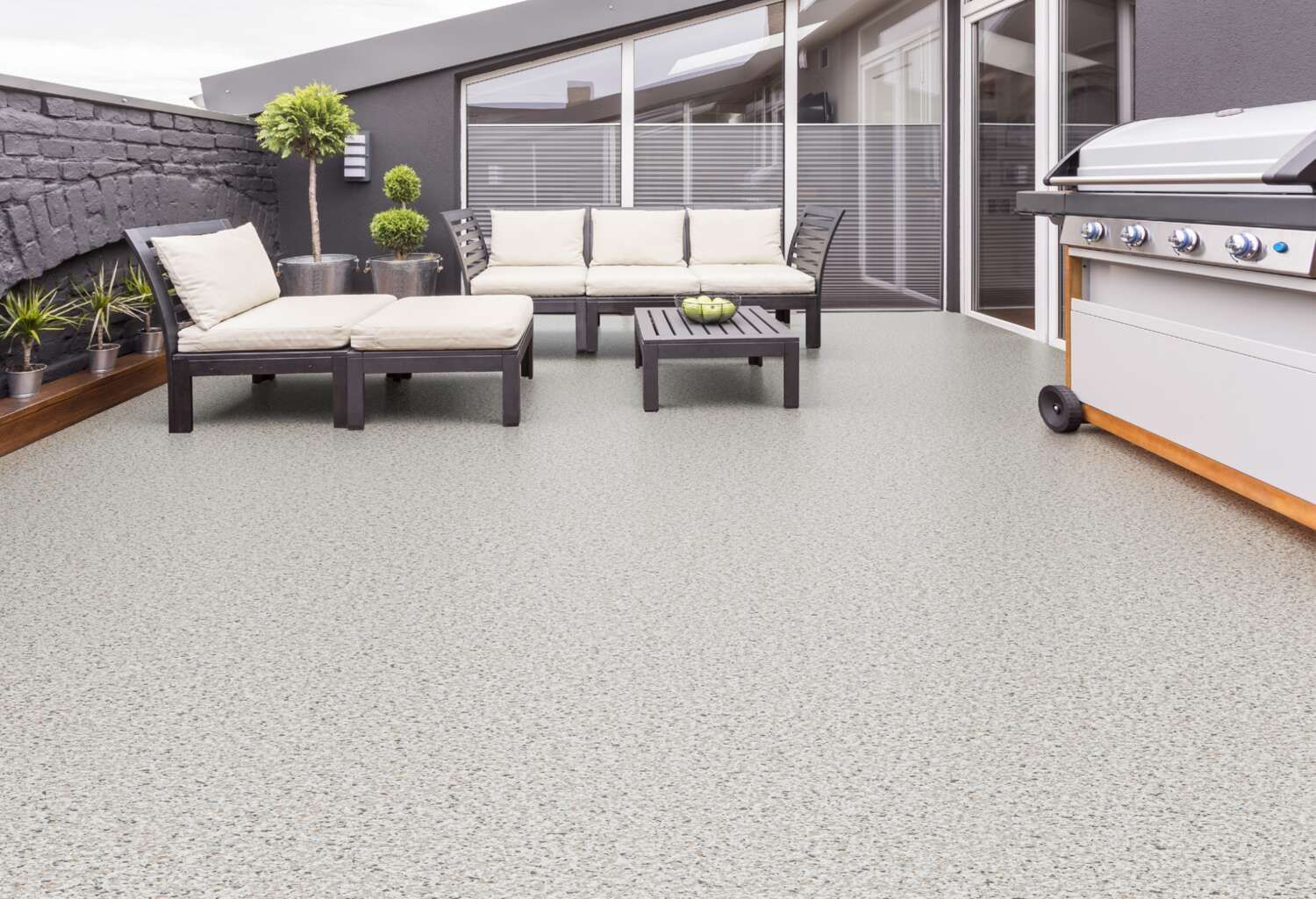 Un patio con divano, tavolo, sedie e barbecue.