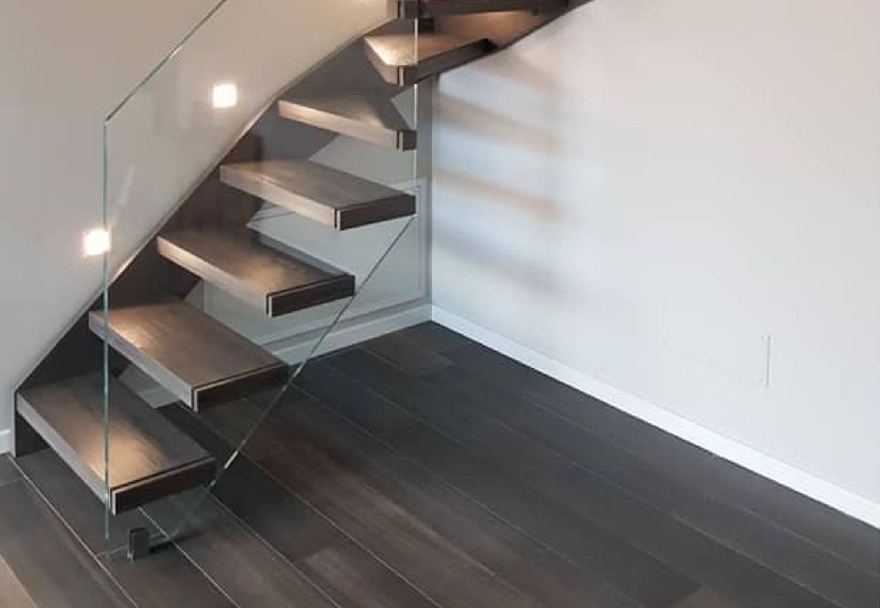 Una scala in legno con ringhiera in vetro in una stanza.