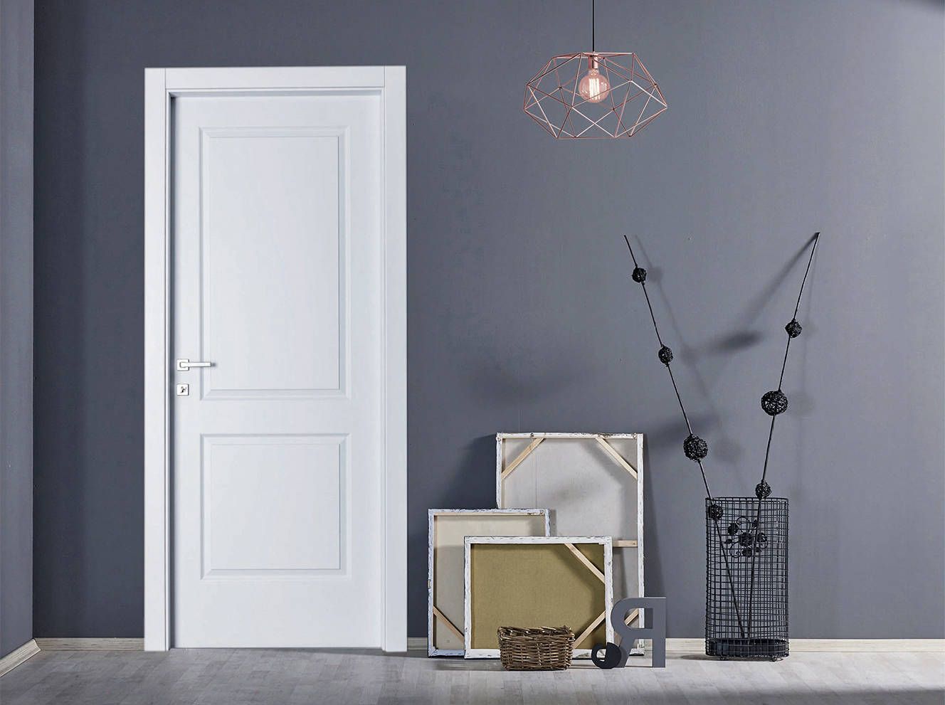 Una stanza con una porta bianca e un mucchio di quadri sul pavimento.