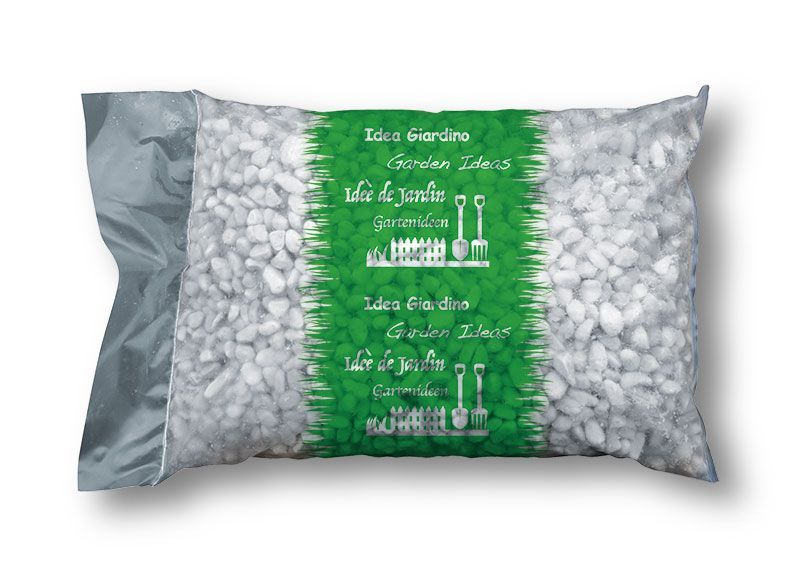 Un sacco di ghiaia è posato su un prato verde.