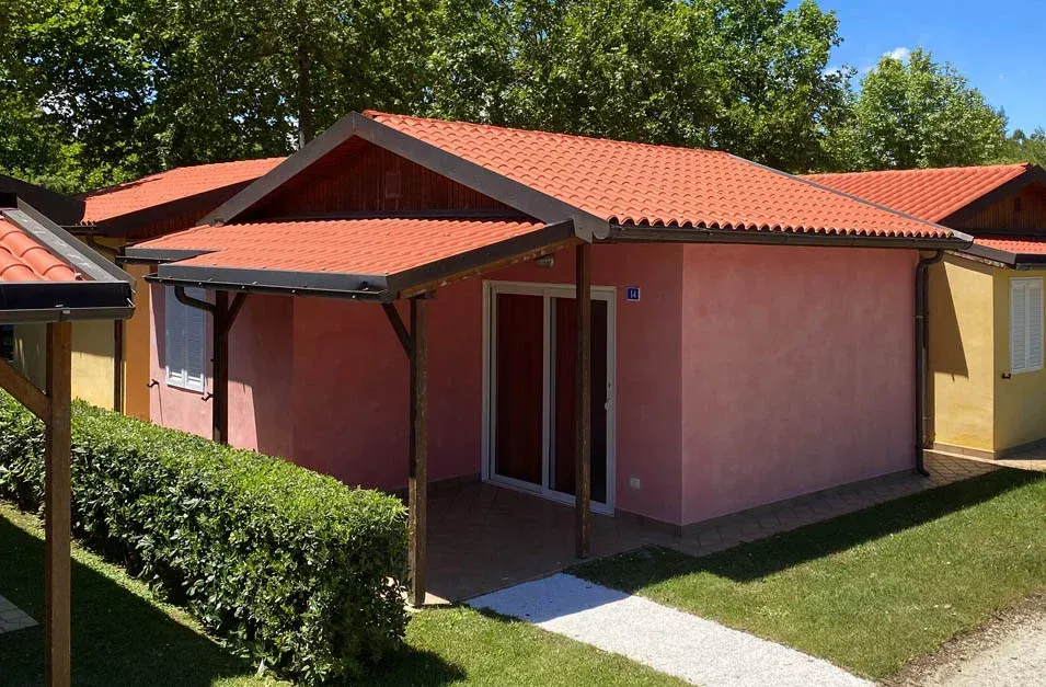 Una casa rosa con il tetto rosso e un portico