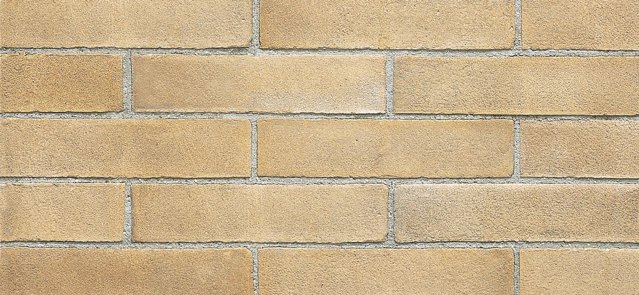 Un primo piano di un muro di mattoni con alcuni mattoni mancanti.