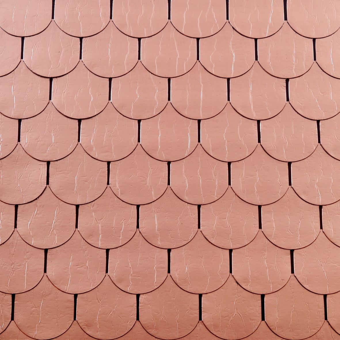 Un primo piano di un tetto di tegole rosse con un motivo a squame di pesce