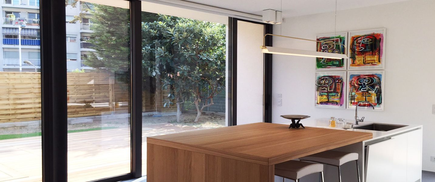 Una cucina con una grande isola in legno e ante scorrevoli in vetro.