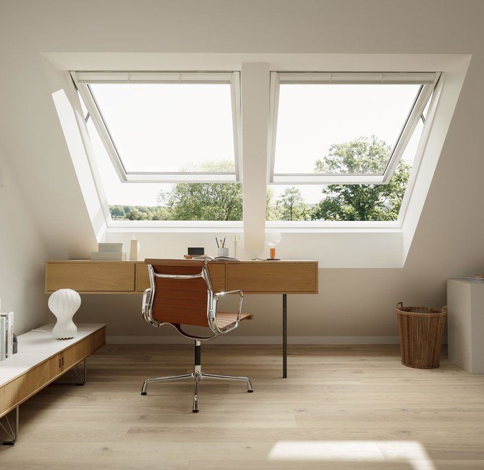 Una stanza con una scrivania e una sedia sotto un lucernario.