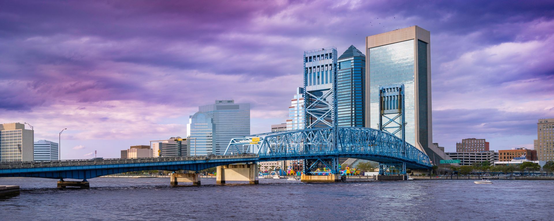 a bridge over a body of water with the jacksonville florida city skyline in the background