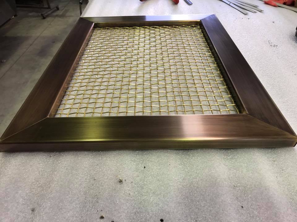 Bronze rectangular frame with gold mesh screen, on a work surface.