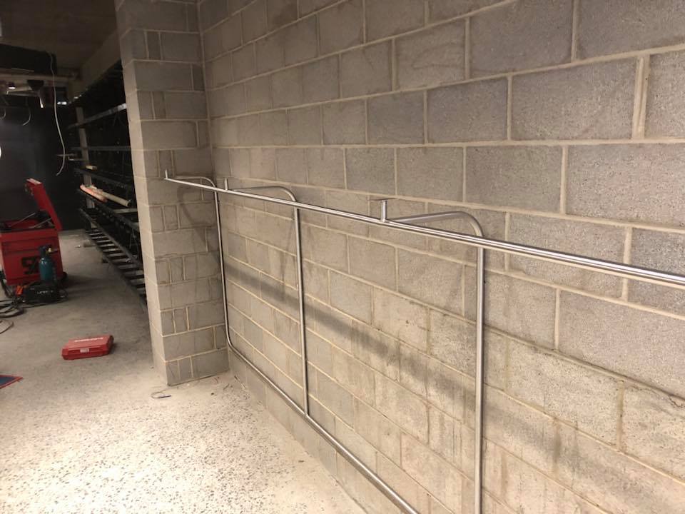 Metal conduit pipes installed on a concrete block wall in an unfinished room.