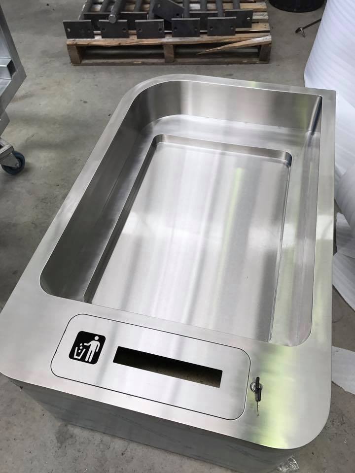 Stainless steel trash receptacle with curved edges and trash/recycling slot.