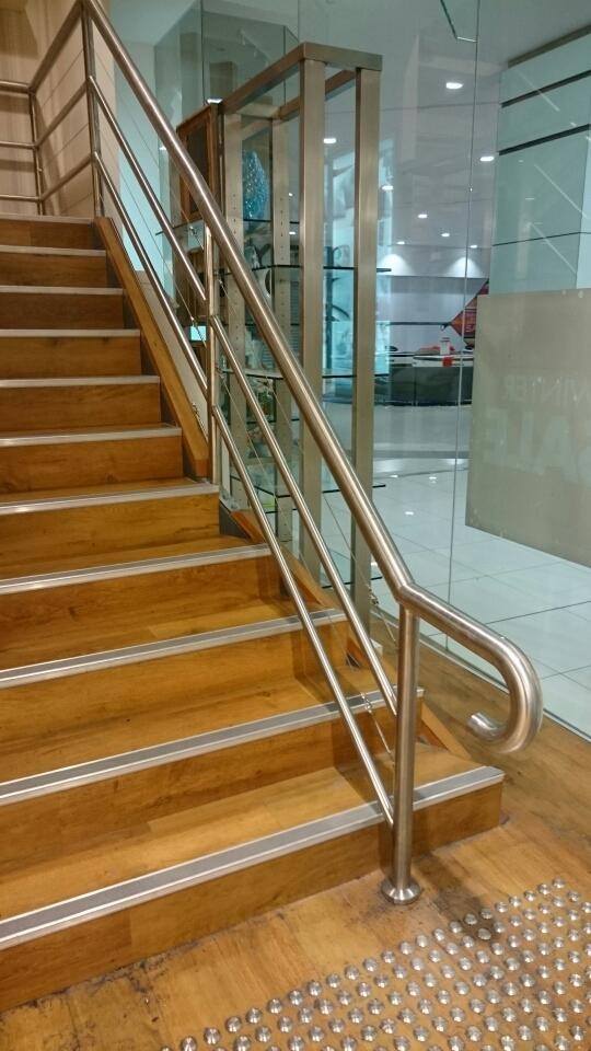 Staircase with wooden steps, metal handrails, and a glass wall.