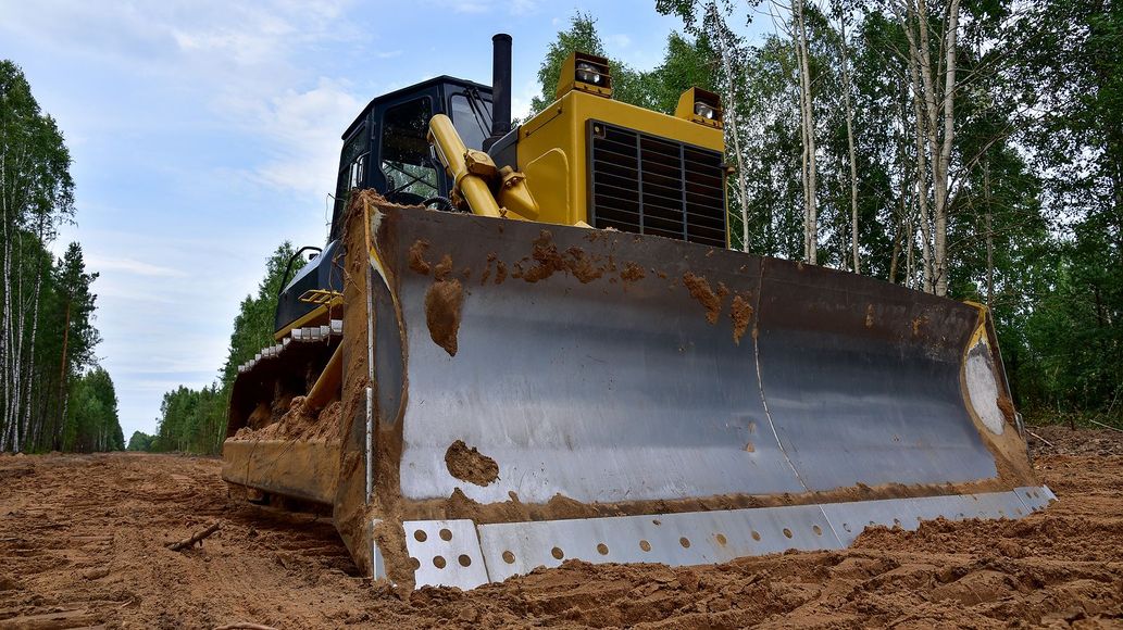 A bulldozer is driving down a dirt road.