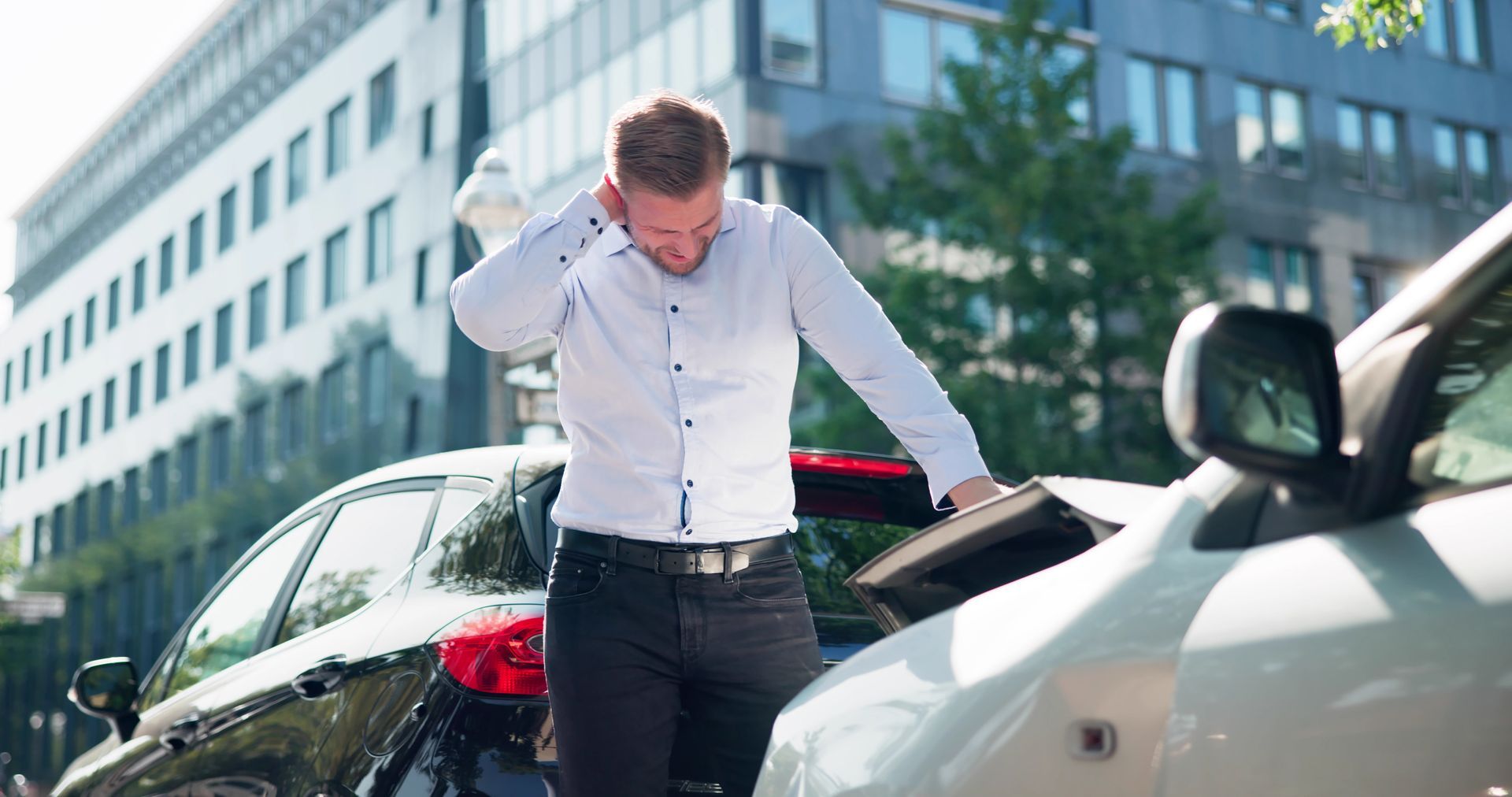 Person standing beside damaged cars after a minor collision, inspecting the impact. Person standing beside damaged cars after a minor collision, inspecting the impact.