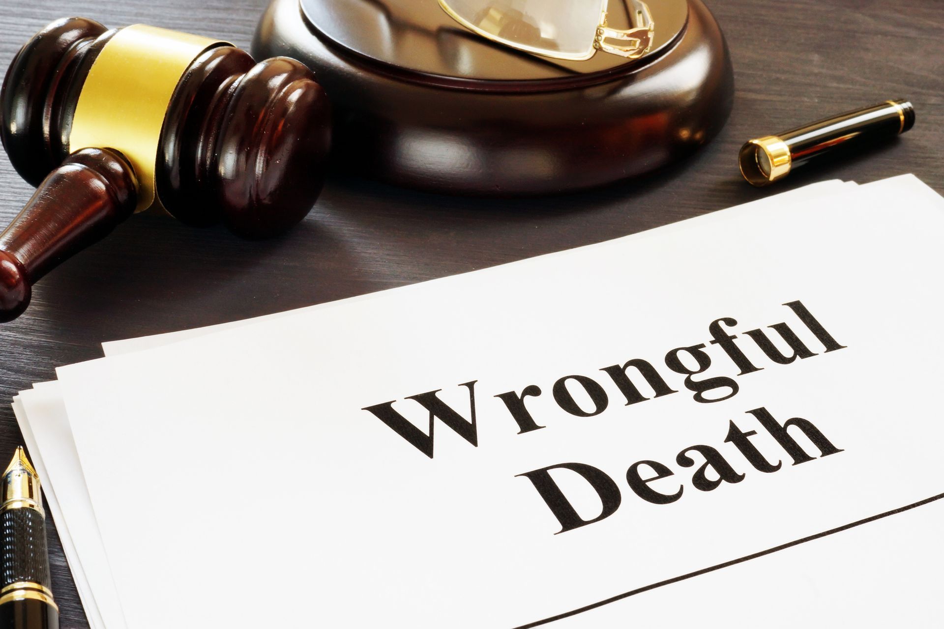 Closeup of a wooden gavel on top of a table with a document that says “Wrongful Death.”