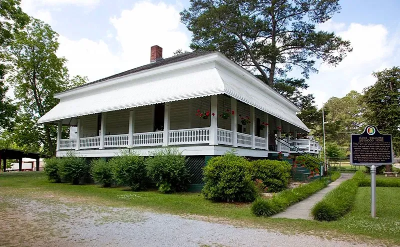 a white house with a porch and a historical marker in front of it