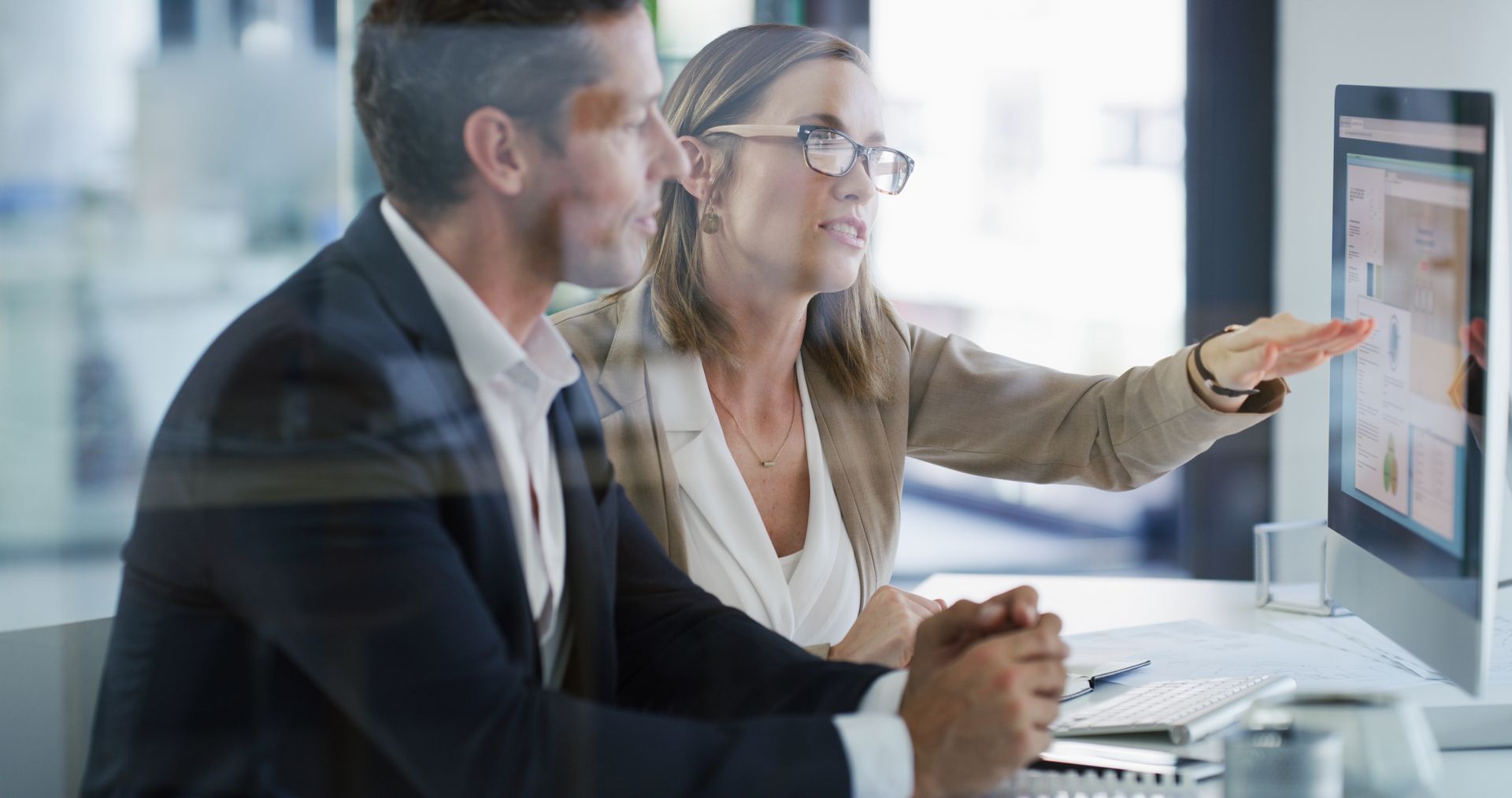 Two professionals in suits at a computer