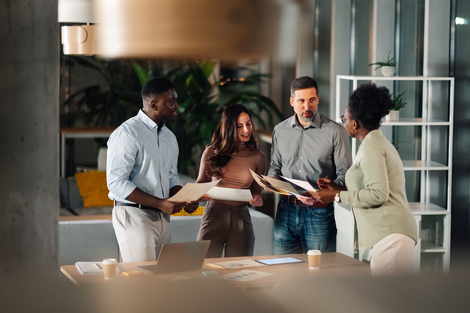 Four people in an office review documents around a table