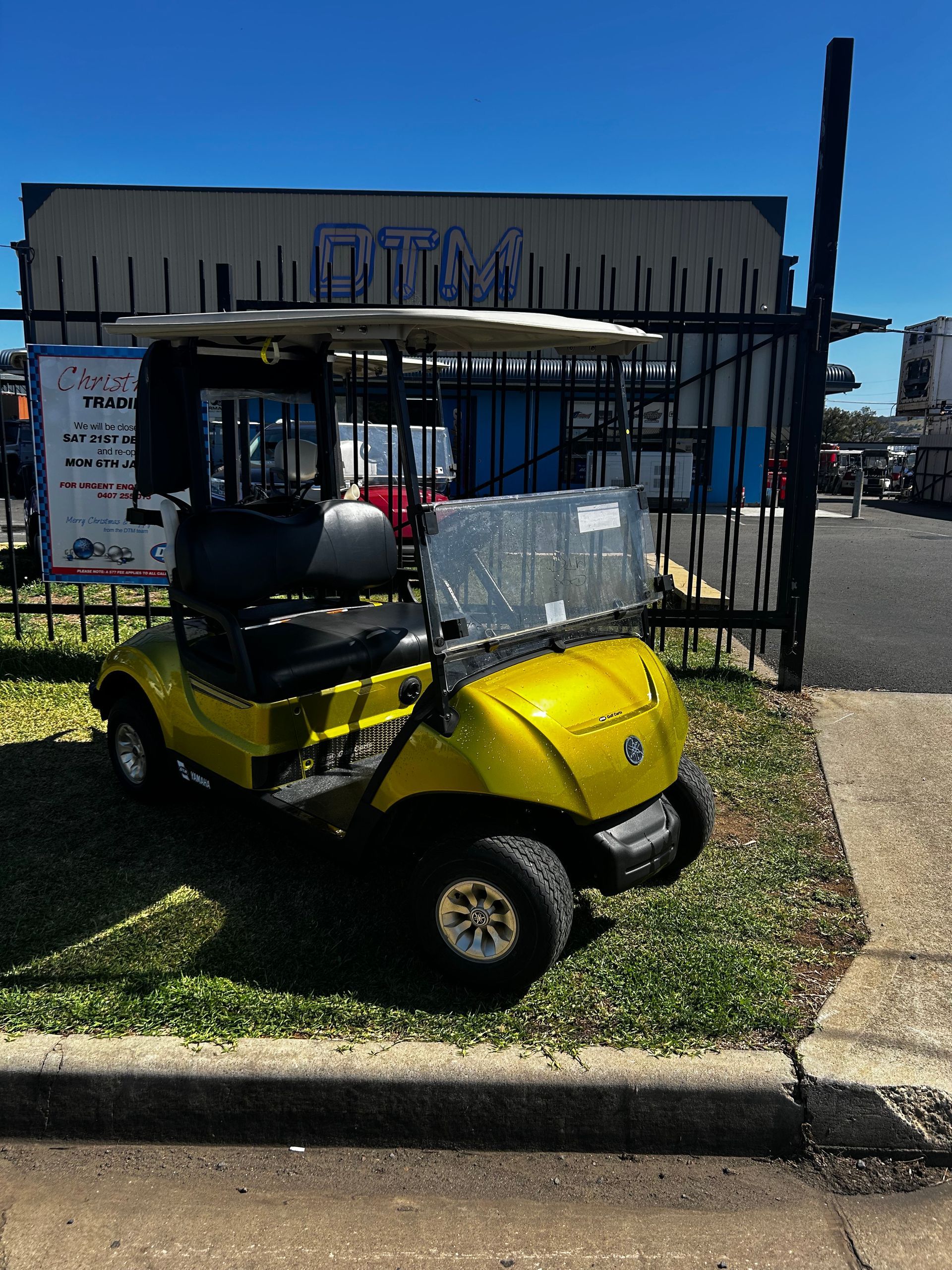 A yellow golf cart parked on an angle on a grass  