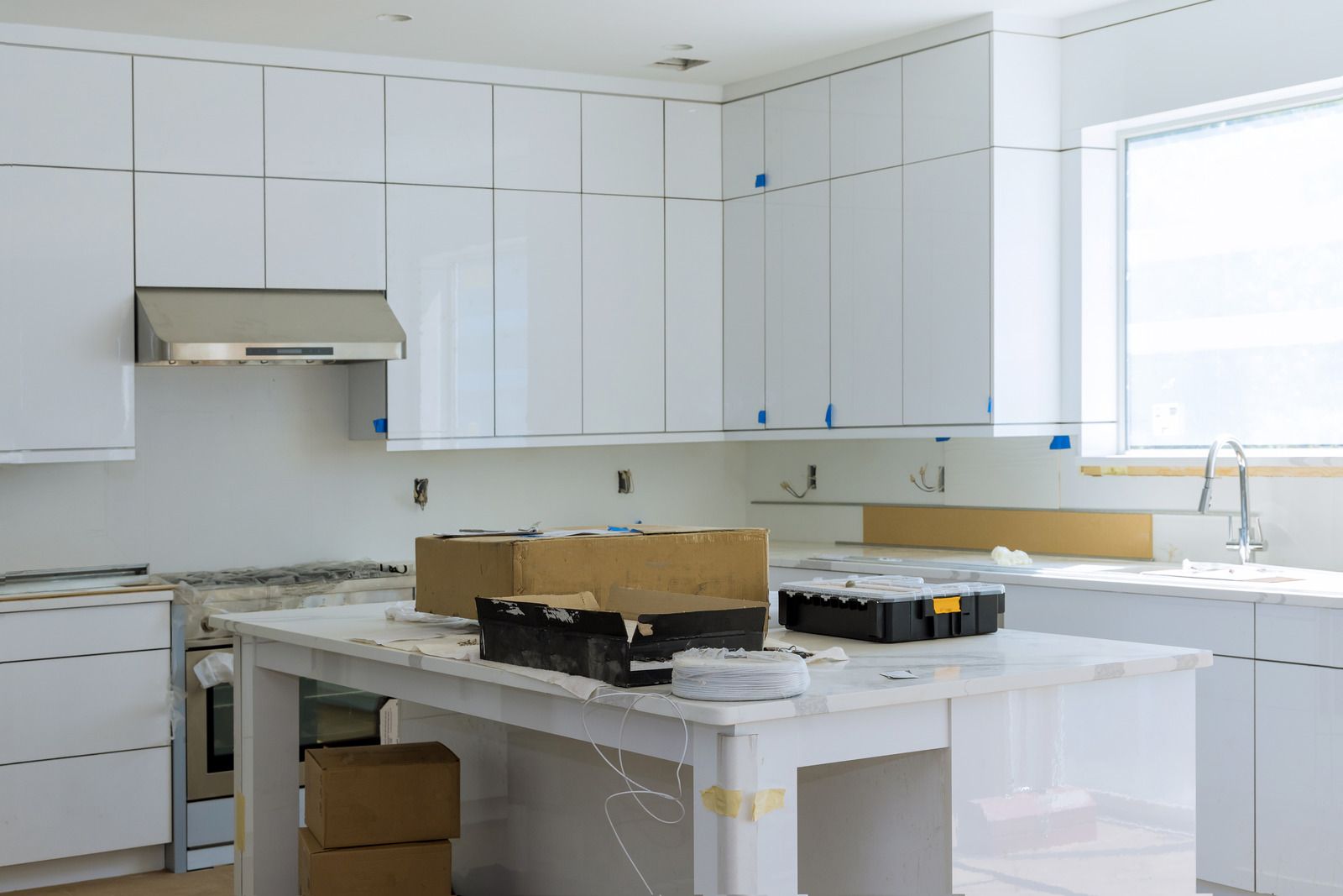 A kitchen under construction with white cabinets and a large island.