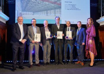 A group of people are standing next to each other on a stage holding awards.