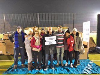 A group of people are standing on top of a blue tarp on a field.