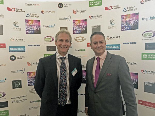 Two men standing in front of a wall with logos on it