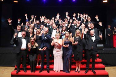 A large group of people are posing for a picture on a stage.