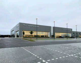 A large Reidsteel  building with a lot of windows and a parking lot in front of it.