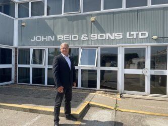 A man in a suit is standing in front of a building.