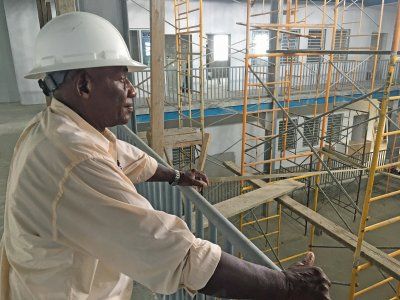 A man wearing a hard hat is standing on a balcony overlooking a construction site.