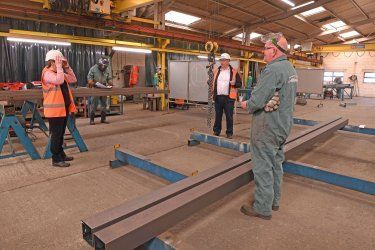 A group of people are standing in a factory talking to each other.