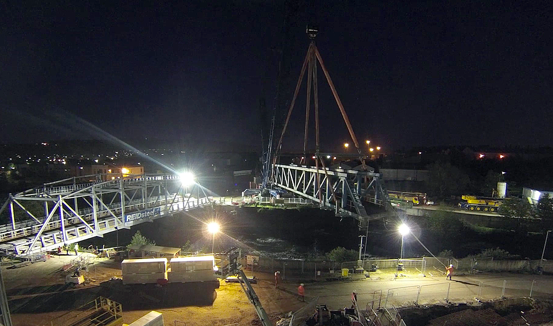 A large crane is lifting a bridge at night