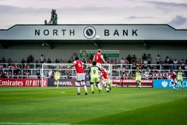 A soccer game is being played in front of a north bank building.