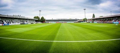 An empty soccer field with a stadium in the background.