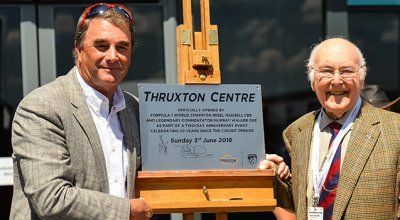 Two men are standing next to each other holding a sign that says thruxton centre.