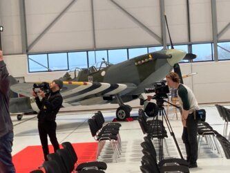 A man is taking a picture of a plane in a hangar.